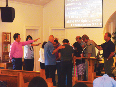 Members of the Hickory Hmong church, as well as district and conference representatives, pray for Jonah and Memee and their family and ministry. Photo: Susan Myer