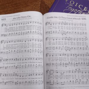 New Voices Together hymnal with purple cover. Book open to page 605 My Life Flown On and page 606 Guide Men, O Thou Great jehovah